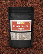 Stone-ground ragi flour in black pouch on finger millet background, nutritious and calcium-rich